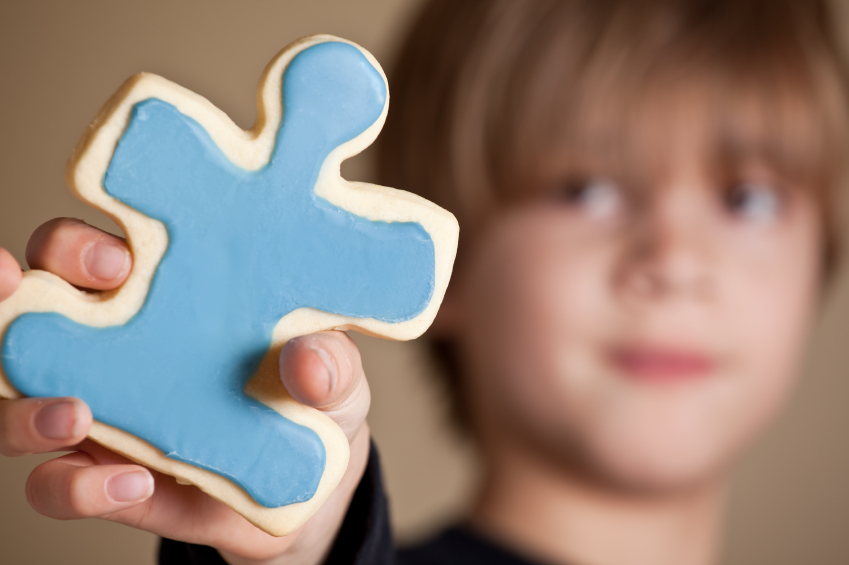 Boy Holding Blue Iced Puzzle Piece Cookie